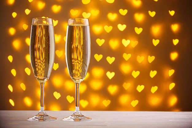 Beautiful glasses of champagne on a blurred background of hearts