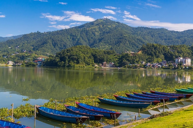 Photo beautiful green phewa lake with boats and green mountains in pokhara city of nepal during monsoon