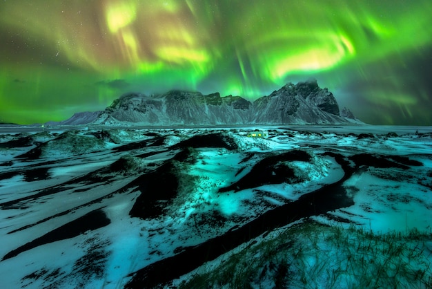 A beautiful green and red aurora dancing over the Vestrahorn, Iceland