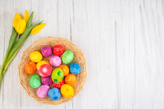 Beautiful group Easter eggs in the spring of easter day, red eggs, blue, purple and yellow in Wooden basket with tulips on the  wood table