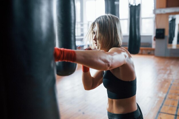 Photo beautiful hair female boxer is punching the bag blonde have exercise in the gym