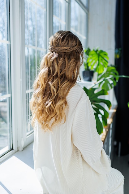 Beautiful hairstyle on long blond hair woman with curls on her head Elegant women's hairstyle with curls