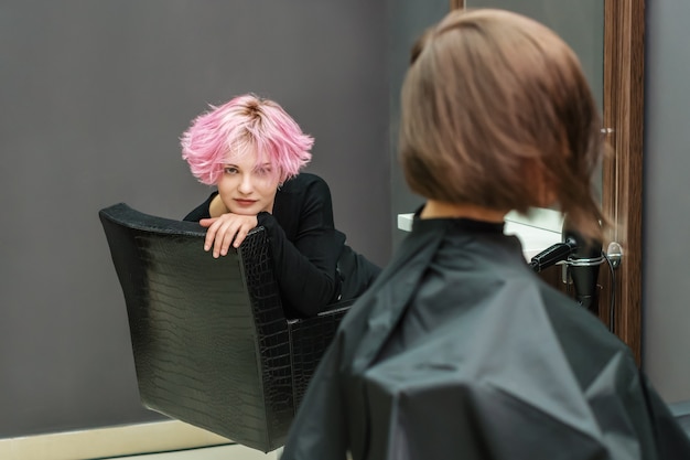 Photo beautiful hairstyle of young woman after dying hair, another woman is doing her hair