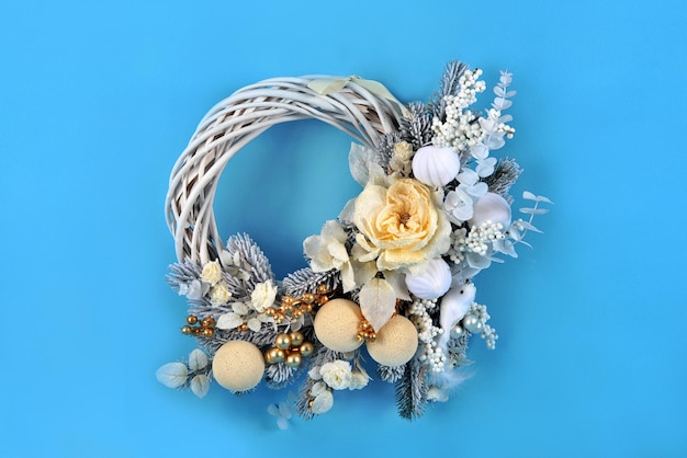 Beautiful handmade Christmas wreath with festive decor on blue background. Christmas composition.