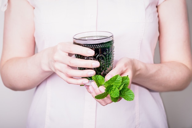 Beautiful hands holding crystal glass of liquid chlorophyll drink