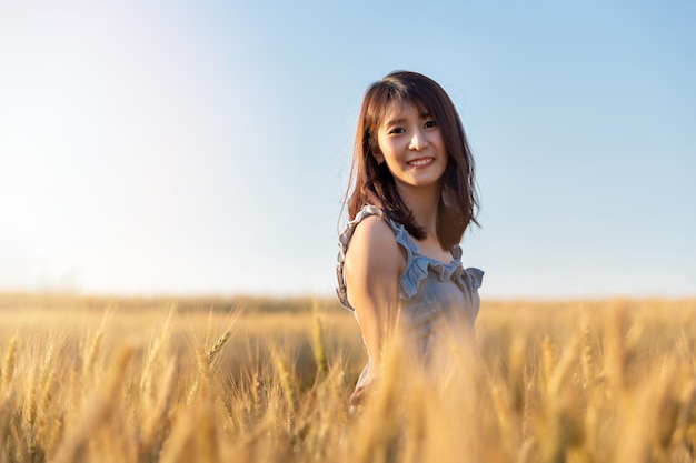 Beautiful and happy asian woman enjoying life in barley field at sunset