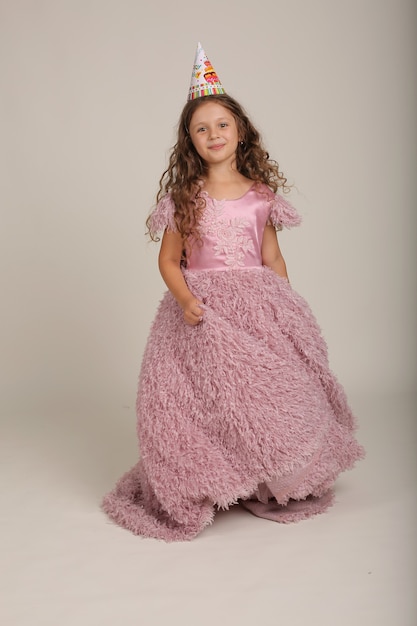 beautiful happy brownhaired girl with curly hair in a pink dress dancing birthday