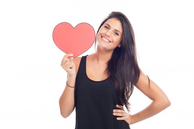 Beautiful happy brunette woman holding and showing a big red heart