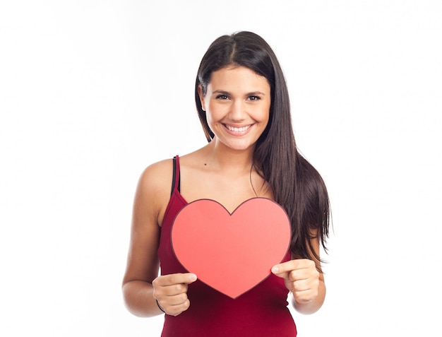 Beautiful happy brunette woman holding and showing a big red heart