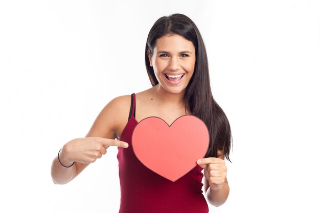 Beautiful happy brunette woman holding and showing a big red heart