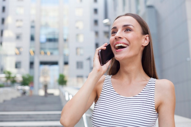 Beautiful happy brunette woman is talking on her smartphone and looking away.