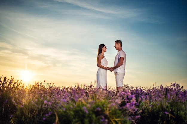 Beautiful happy couple in a lavender field. Fantastic summer mood, floral sunrise landscape of meadow lavender flowers.