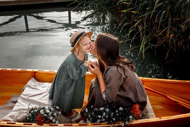 Photo beautiful happy family mother and daughter in a wooden boat  on the lake together