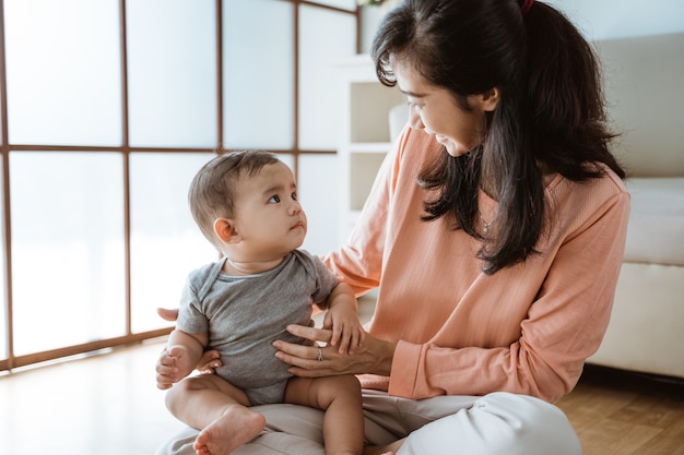 Beautiful happy mother playing with her baby at home