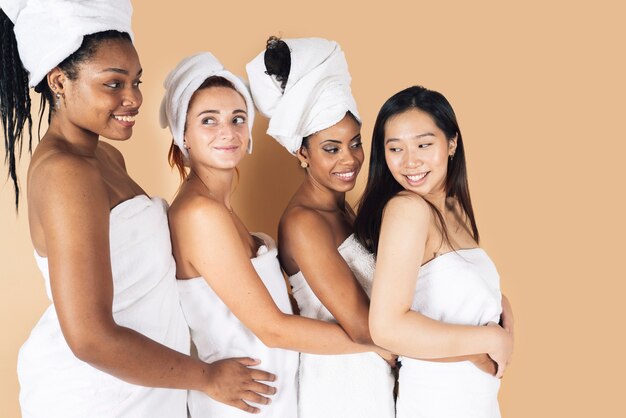 Beautiful happy multiethnic women wear white bathrobes on head skincare spa relaxation