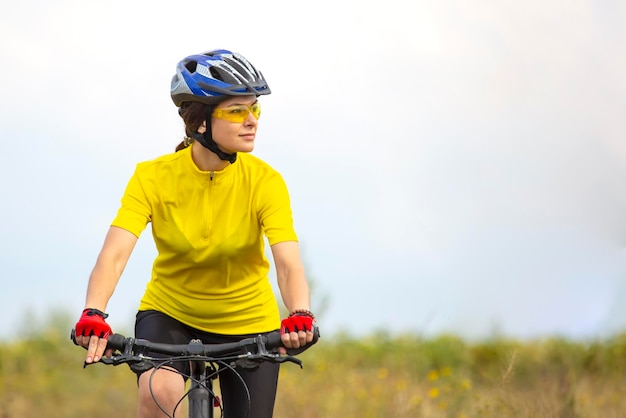 Beautiful and happy woman cyclist rides a bicycle on the road in nature Healthy lifestyle and sports Leisure and hobbies