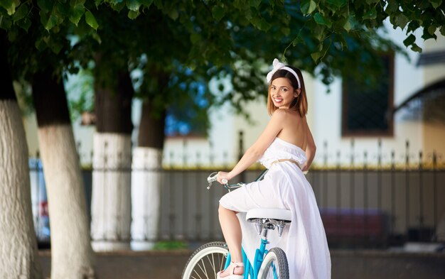 Beautiful happy woman riding bike in the city