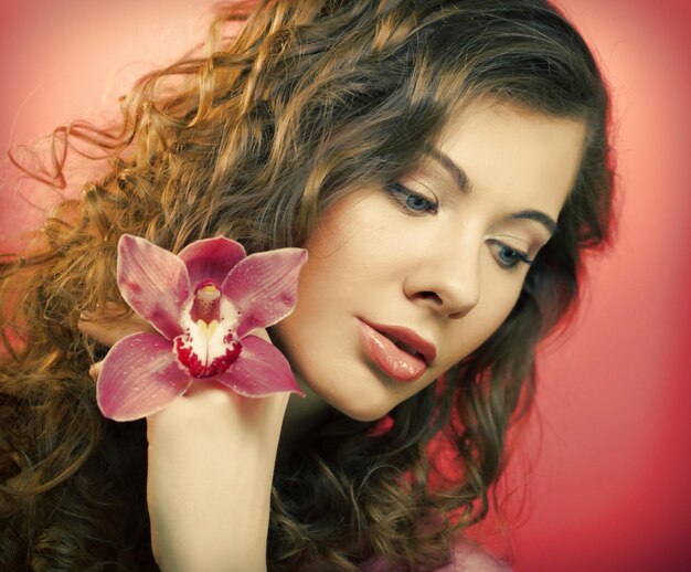 Beautiful happy woman with orchid flower over pink background