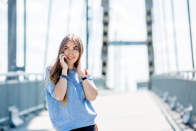 Beautiful happy young businesswoman using cell phone on city street