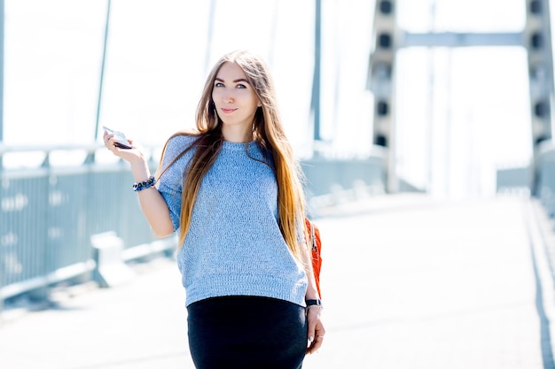 Beautiful happy young businesswoman using cell phone on city street