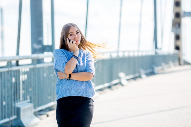 Beautiful happy young businesswoman using cell phone on city street