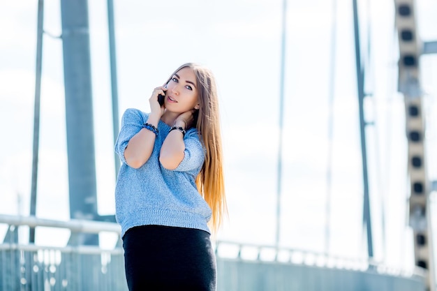 Beautiful happy young businesswoman using cell phone on city street