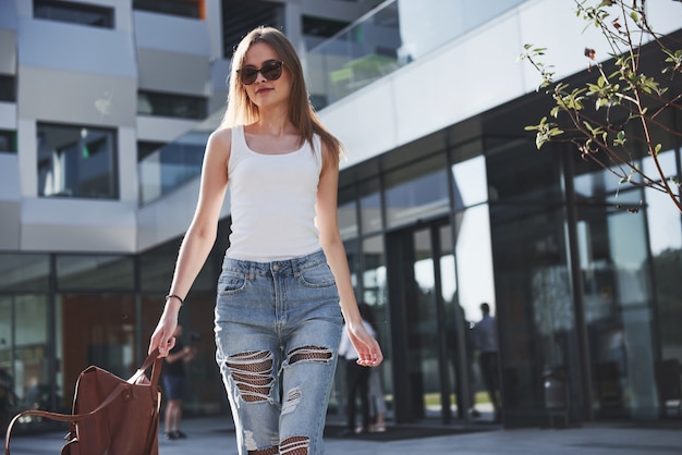 Beautiful, happy young student girl with backpack near the campus of university. Education and leisure concept