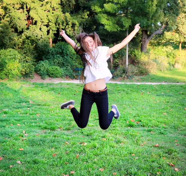 Beautiful happy young teen girl jumping high in the park