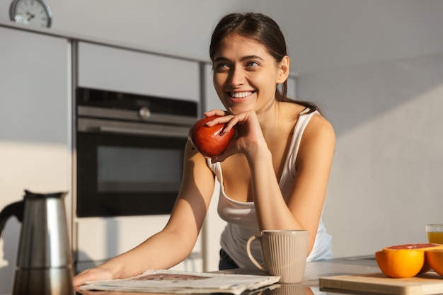 Beautiful healthy woman in the kitchen with apple morning routine.