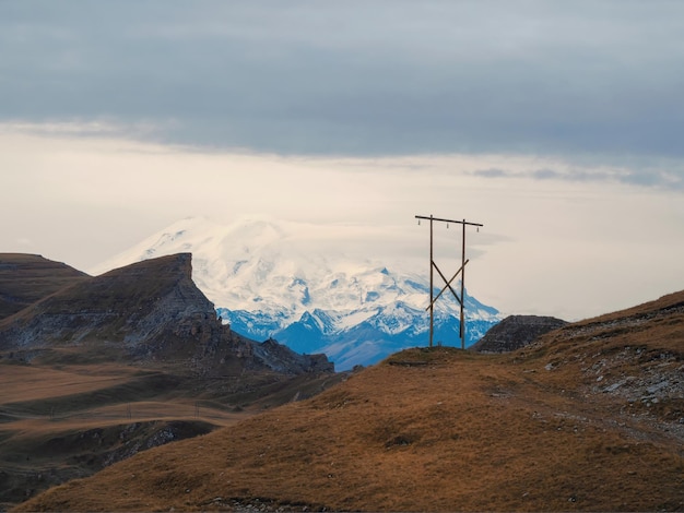 Beautiful highaltitude plateau with a telegraph pole on the background of the snowcovered Mount ElbrusThe Bermamyt plateau in KarachayCherkessia