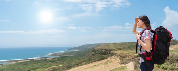 beautiful hiker hiking to the top of the mountain happy to enjoying the beautiful sea scenery and sunny sky in the summer vacation. banner crop for copy space.