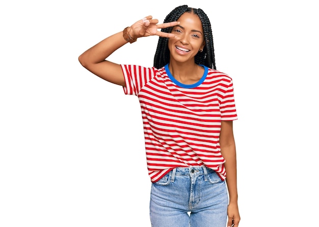 Beautiful hispanic woman wearing casual clothes doing peace symbol with fingers over face smiling cheerful showing victory