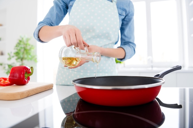 beautiful housewife hold olive oil pouring hot frying pan