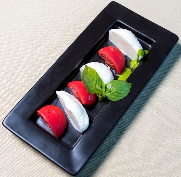 Beautiful ice cream balls with tomato on the black plate