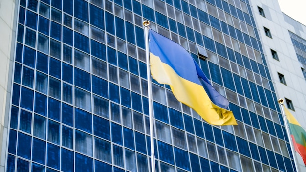 Beautiful image of Ukrainian flag fluttering on wind against high modern office building