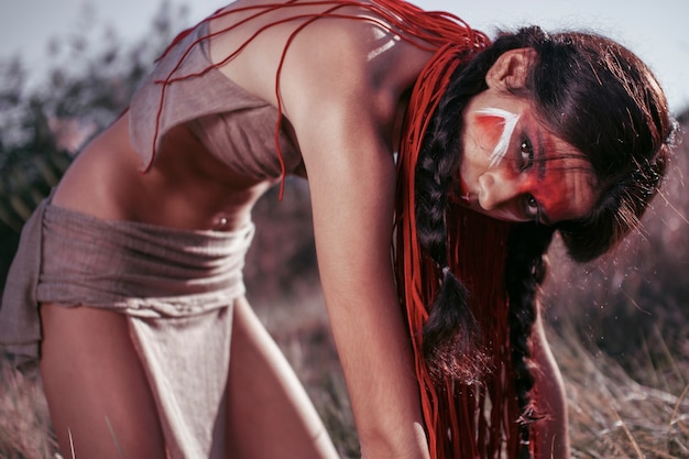 Beautiful Indian woman works in the field, red make-up on her face. bent posture. close-up