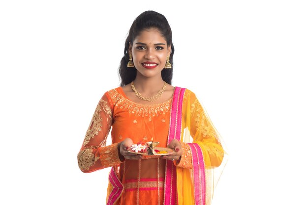 Beautiful Indian young girl holding pooja thali or performing worship on white