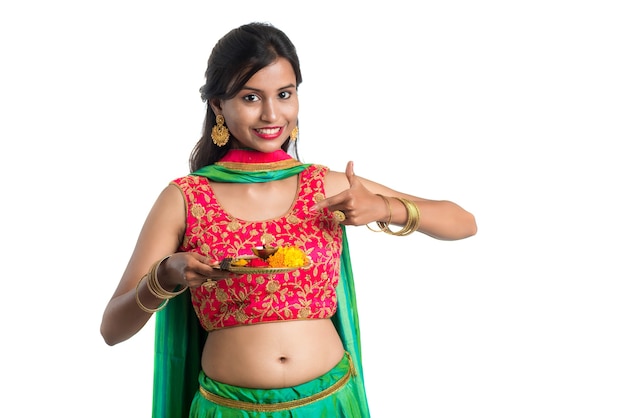 Beautiful Indian young girl holding pooja thali or performing worship on a white