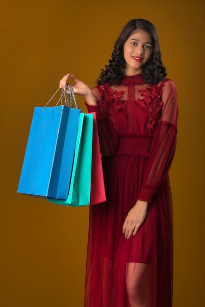 Beautiful Indian young girl holding and posing with shopping bags on a brown background