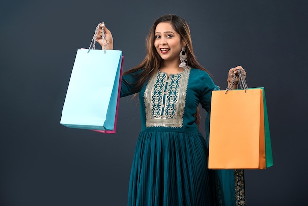 Beautiful Indian young girl holding and posing with shopping bags on a grey background