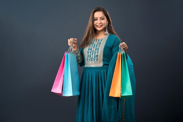 Beautiful Indian young girl holding and posing with shopping bags on a grey background