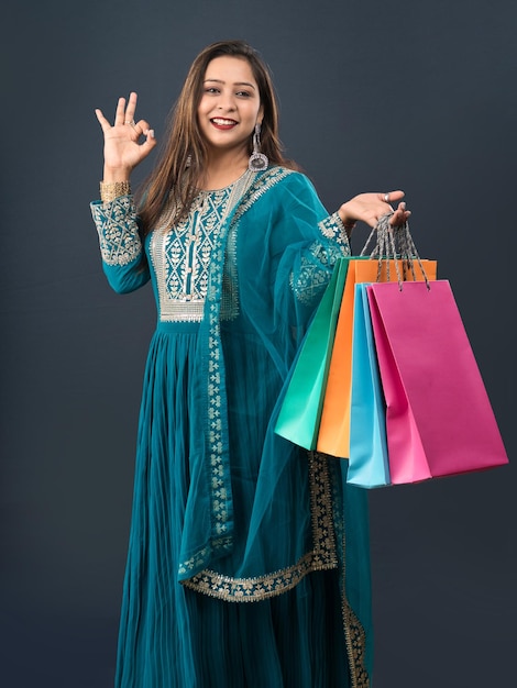 Beautiful Indian young girl holding and posing with shopping bags on a grey background