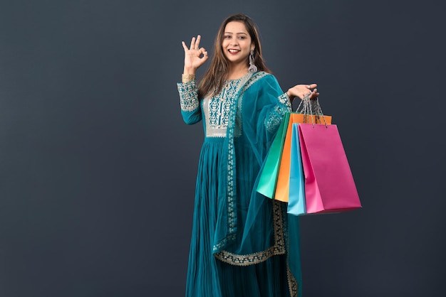 Beautiful Indian young girl holding and posing with shopping bags on a grey background