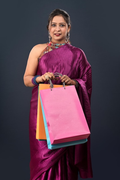 Beautiful Indian young girl holding and posing with shopping bags on a grey background