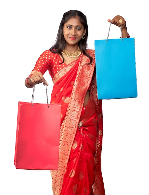 Beautiful Indian young girl holding and posing with shopping bags on a white background