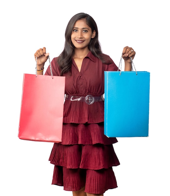 Beautiful Indian young girl holding and posing with shopping bags on a white background