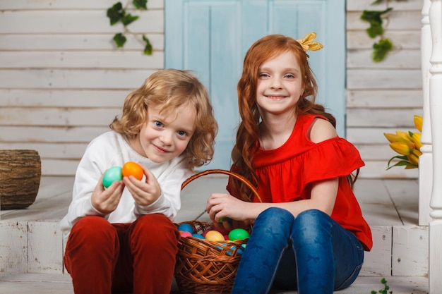 Beautiful kids sit together with a basket of Easter eggs and have fun. Funny moments