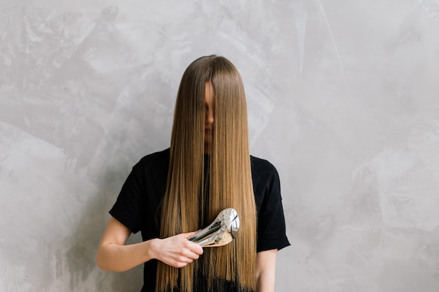 Beautiful lady doing her make up and hair in bedroom. Attractive young female with pretty long hair