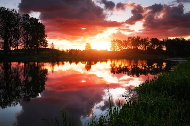 Beautiful landscape with fiery sunset over the lake. View from the coast