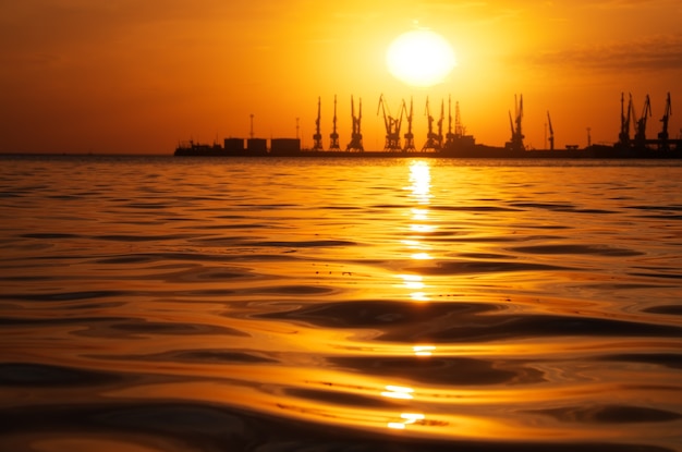 Beautiful landscape with fiery sunset sky and sea. Harbor of Berdyansk during sunrise. 